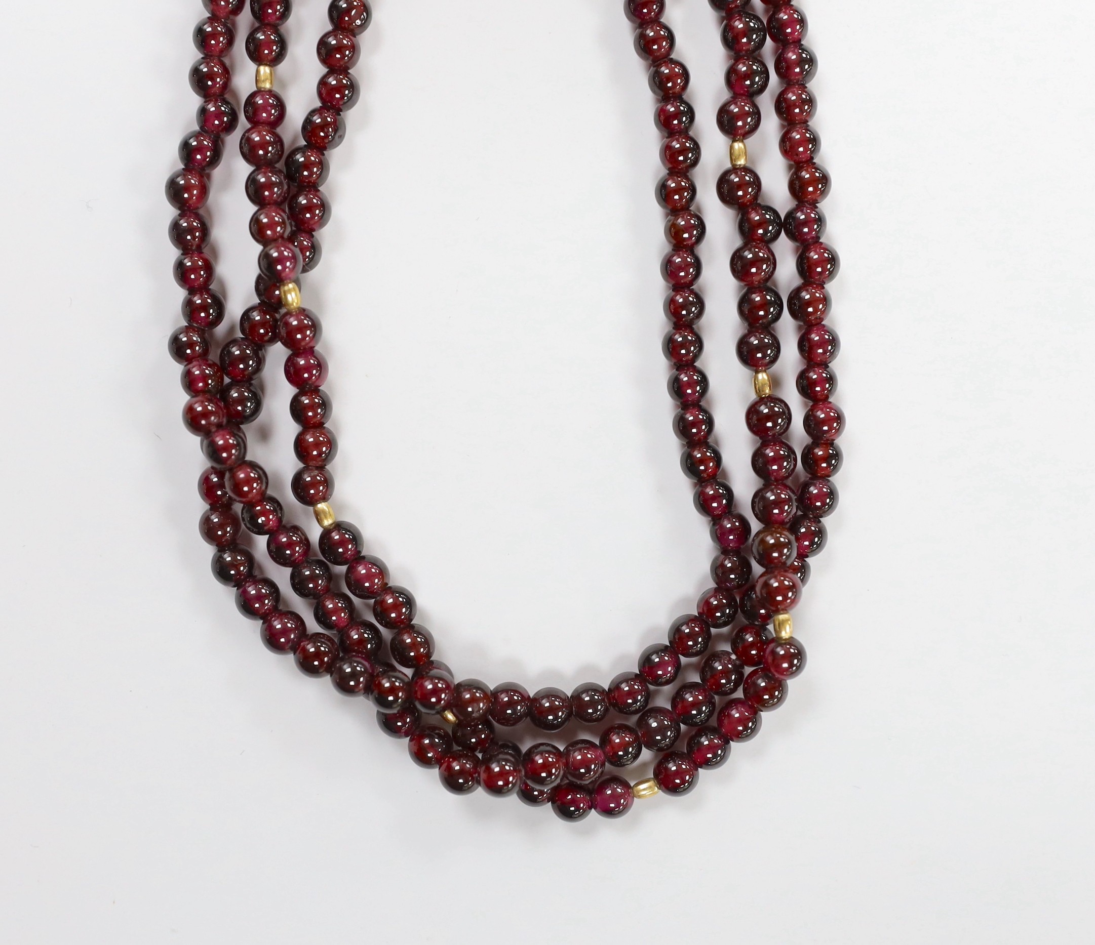 A Tiffany & Co triple strand garnet bead necklace, with 750 clasp and spherical spacers, 48cm, in a Tiffany & Co box.